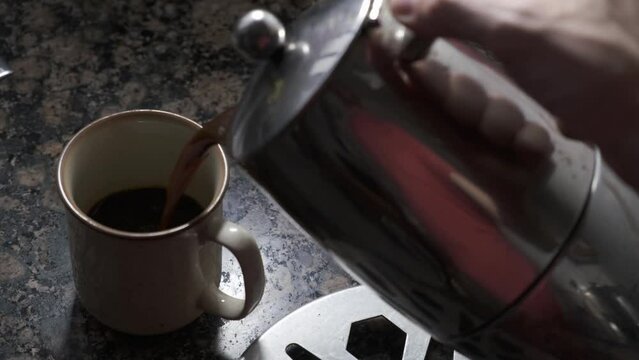 hand  serving coffee in cup in the kitchen, close up