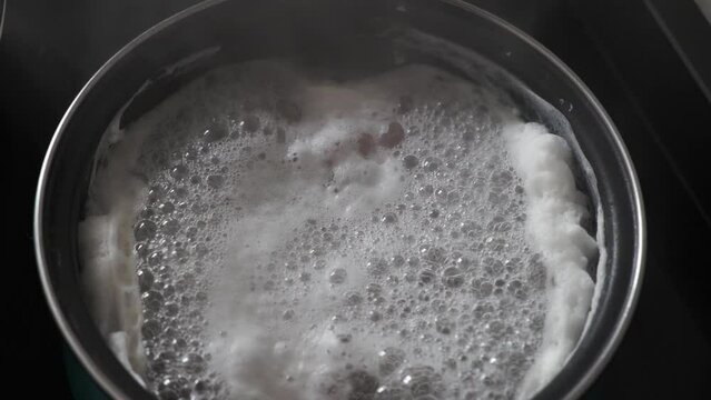 cocer o hervir alimento con agua en cacerola en la cocina 