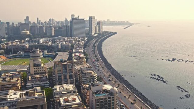 Aerial view of Marine Drive at Mumbai India. Girgaon Chowpatty Seaface aerial drone view, Local train speeding along the tracks as it travels through the bustling cityscape of Mumbai.