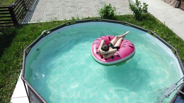 handsome boy swim in swimming pool water with rubber ring. aerial dron view