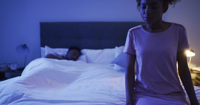 Couple fighting, anxiety and a black woman on the bed with her husband sleeping at night. Insomnia, infertility or sleepless with a young wife looking worried, sitting in the bedroom of her home