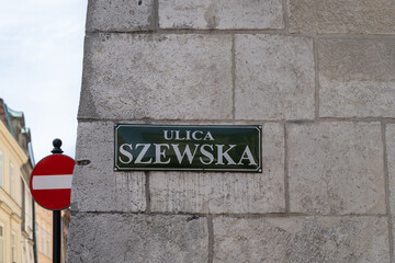 Szewska street name sign in the Old Town district of Krakow, Poland. Information plate on building...