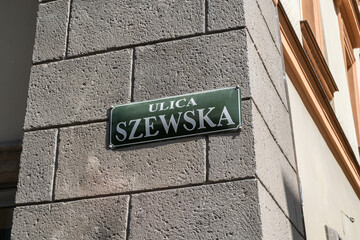 Szewska street name sign in the Old Town district of Krakow, Poland. Information plate on building wall in Kraków. One of the main historic promenades of Cracow, that begins at the Main Square Market.