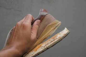 Torn brown footwear sneaker with broken sole., its sole peeled back and damaged.