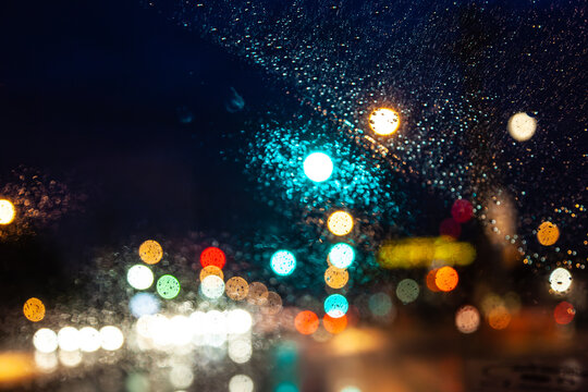 traffic light with red arrow in storm  and dark rain clouds defocused as light symbols seen from car windshield, USA