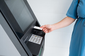 A faceless woman inserts a credit card into an ATM. Close-up of a woman's hands using an ATM machine.
