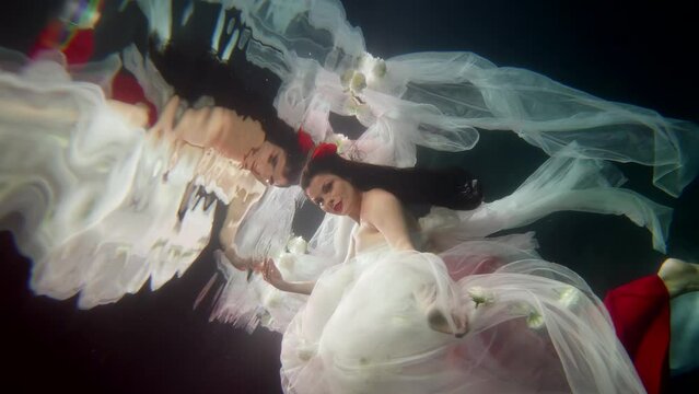 underwater princess and reflection in water surface, pretty brunette swimming in magical depth