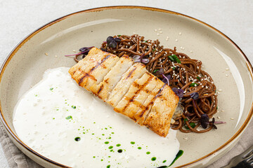 Portion of halibut fillet with soba noodles and creamy sauce