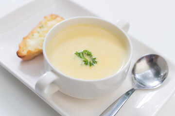 Delicious corn soup In a white bowl served with bread