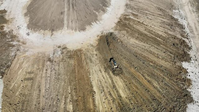 Aerial view, the skidster pushes the soil from the top of the mountain to the bottom. A mountain slope is being formed.