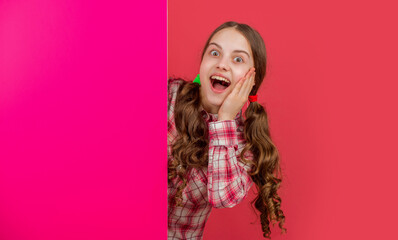 amazed teen child behind blank pink paper with copy space for advertisement