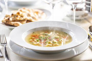 Hot chicken soup with small tortellini, carrot and greens on top