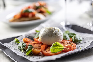 Caprese style salad with sliced tomatoes, basil and ball of buffalo mozzarella.