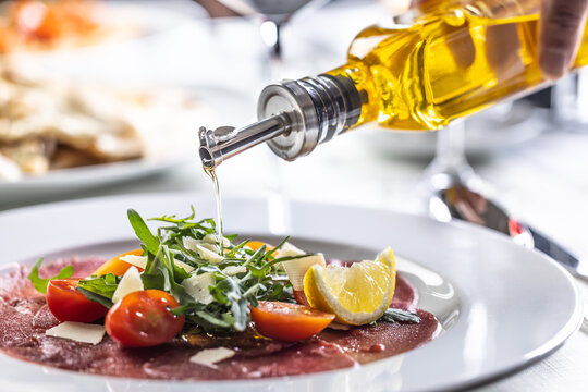Olive oil poured over a rocked salad in a carpaccio appetizer