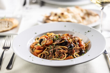 All'amatriciana pasta with tomatoes, olives and pancetta in a plate