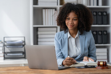 American woman lawyer or businesswoman African working with laptop searching for information, reading codes, documents, studying constitution to protect rights work with law books hammer of justice.