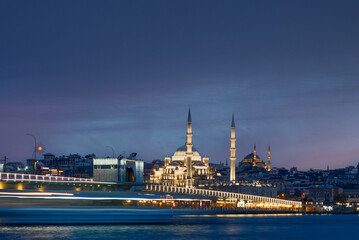 Long exposure of Istanbul at dusk with boats passing by Bosphorus canal and mosque. Scenic view of Istanbul in Turkey with Galata bridge at night.