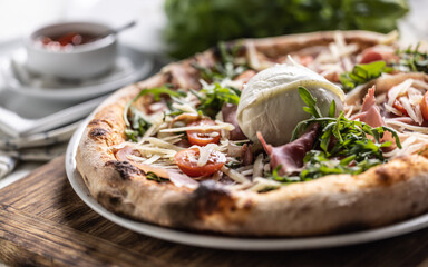 Ham, ruccola, tomatoes and cheese pizza with entire mozzarella di bufala Campana on top
