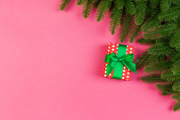 Top view of fir tree branches and gift box on colorful background. Christmas time concept with empty space for your design