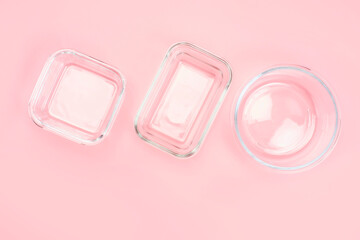 Empty open glass lunch boxes on pink background up close-up.