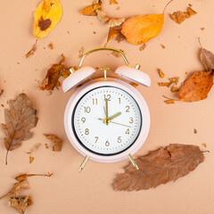 Alarm clock with autumn foliage, end of daylight saving time in fall, winter time changeover

