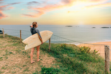 Young surfer woman putting her hair up while looking at the beach from the shore