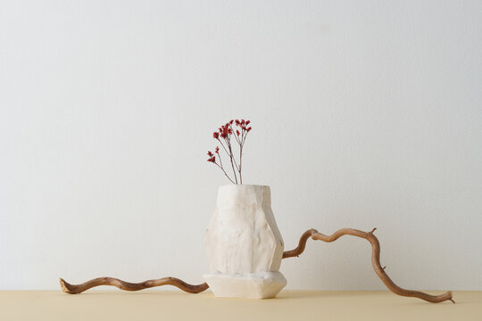 Horizontal shot of contemporary still life composition with gypsum vessel, dried flowers and branch against white wall background, copy space