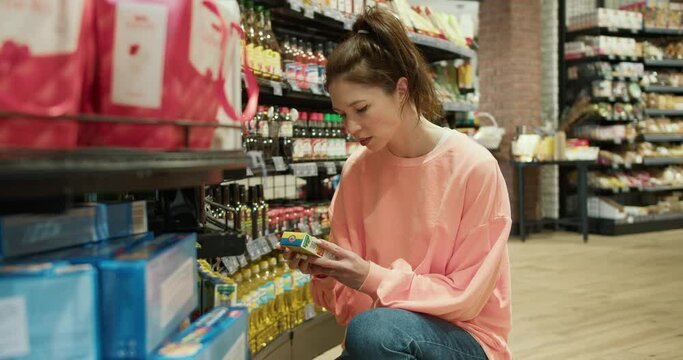 Everyday Delights: Young Woman in Peach Sweater Embraces the Simplicity of Supermarket Shopping