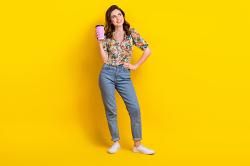 Full body photo of young thinking girl hold plastic cup coffee cappuccino look dream empty space energy isolated on yellow color background