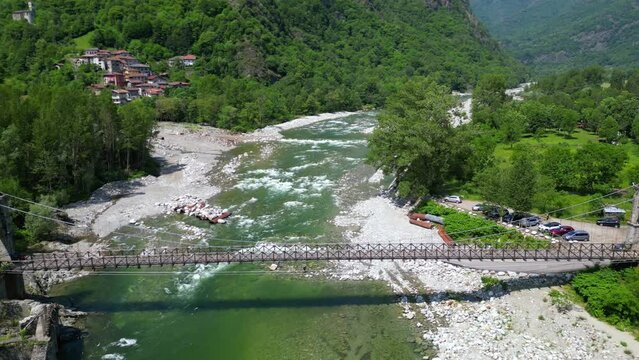 Drone flight over a wooden Tibetan suspended bridge that joins the river banks - view from the drone in Alagna Val Sesia Piedmont Alps mountains - travel concept journey in adventure natural trip 