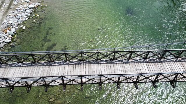 Drone flight over a wooden Tibetan suspended bridge that joins the river banks - view from the drone in Alagna Val Sesia Piedmont Alps mountains - travel concept journey in adventure natural trip 