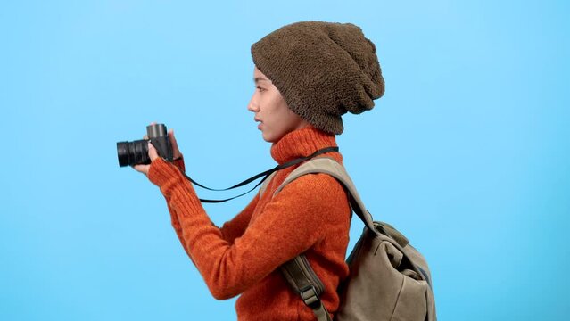 Asian tourists travel in winter using camera for photos, Young photographer sightseeing and using lens to make memories, city break abroad, taking pictures isolated on blue background.