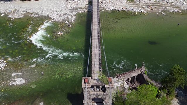 Drone flight over a wooden Tibetan suspended bridge that joins the river banks - view from the drone in Alagna Val Sesia Piedmont Alps mountains - travel concept journey in adventure natural trip 