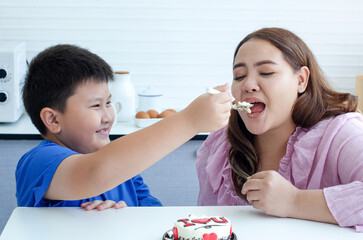 Obese mother and son enjoying cake, child boy feeding his mother, selective focus, examples of bad eating habits