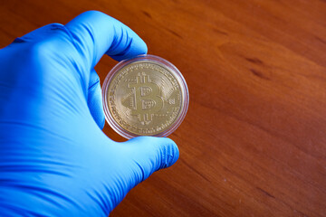 A golden metal coin was shown and held in blue disposable protective rubber gloves.