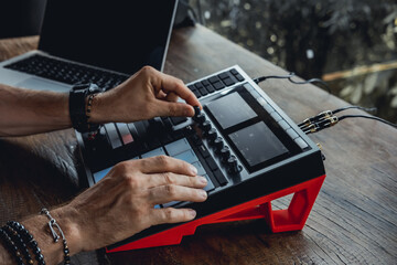 young handsome man with a beard and dark hair sits at a table and creates music, listens to headphones, writes songs, musician portrait, concept, laptop, monitor speakers, pianist, recording studio