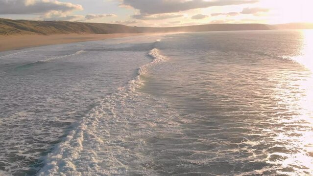 The stunning aerial shot of Perran Sands during sunset, the waves are calm and there's a serene vibe in the air