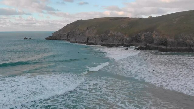 The stunning aerial shot of Perran Sands during sunset, surfers are in the water waiting to catch a perfect wave