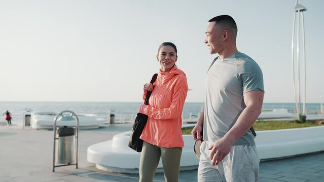 Smiling multicultural couple go exercising by sea at dawn