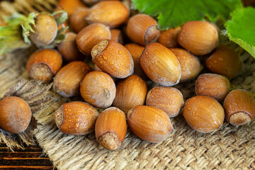 Hazelnuts on a wooden background with green leaves. Contains beneficial vitamins and minerals.
