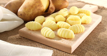 Uncooked gnocchi on cutting board. italian potato noodles on a wooden background. traditional mediterranean cuisine. famous italian potato dish. food on a rustic table on a sunny day.