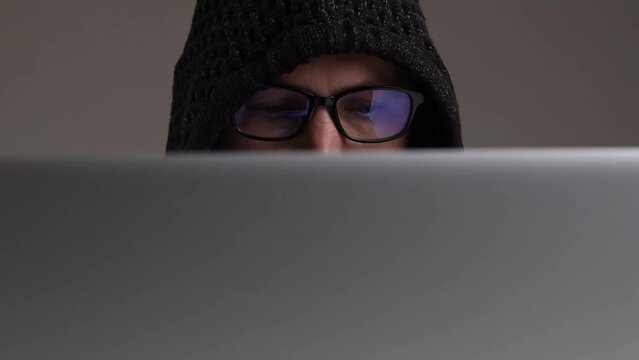 Man In Hooded Glasses Typing While Sitting On A Laptop