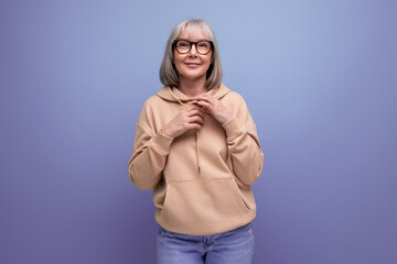 portrait of a kind middle-aged woman grandmother with gray hair in a casual youth look on a studio background with copy space