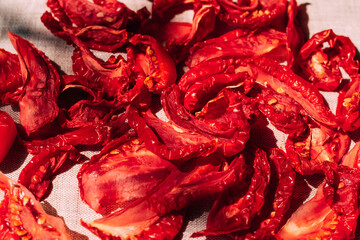 Appetizing sun-dried tomatoes lie on the kitchen table, bright sunlight and shadow, top view. Harvesting and processing vegetables, organic food