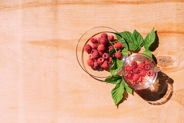 Ripe red raspberry drink in a transparent glass wooden background, summer seasonal food and refreshing drinks
