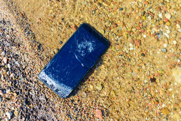 Vacation problems.Accident with smartphone. Smartphone falling and crashing on the beach.Cell phone...
