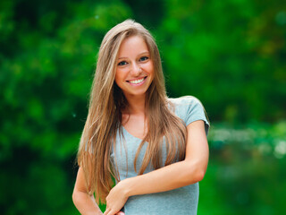 portrait of young smiling attractive caucasian woman in jeans jacket in the park at summer