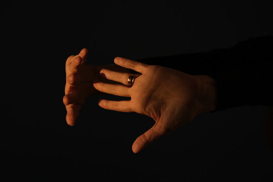 Sunlit female hands are visible on a dark background
