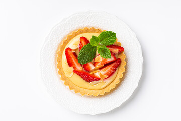 Overhead shot of strawberry mini cake tartlet with vanilla custard and mint leaves over white background. Concept of homemade sweet pastries. Copy space, top view - obrazy, fototapety, plakaty