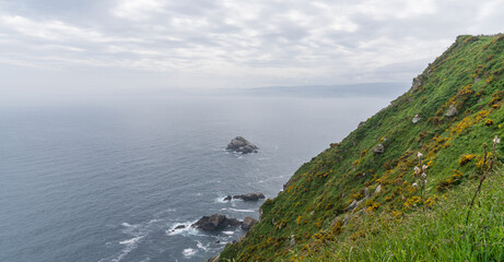 Fototapeta premium Nature landscape rocky cliff shore. Cabo Ortegal lighthouse with the sea in the background on the coast of Galicia, Spain, Europe. Majestic coastline looking the Atlantic Ocean.